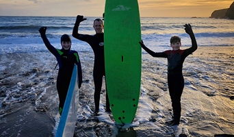 Surfers posing with green surfboard.